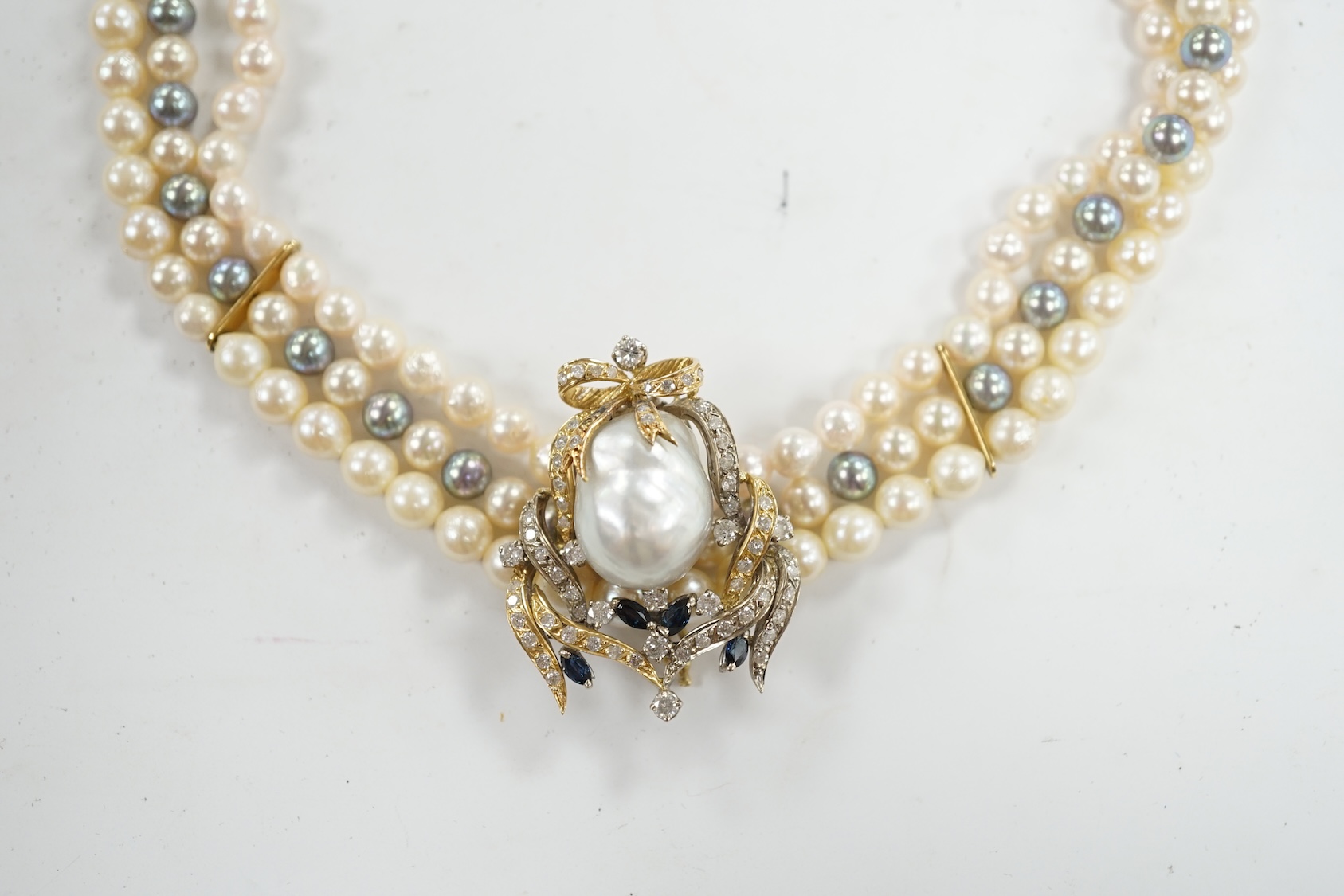 A modern triple strand two colour cultured pearl necklace, with yellow metal clasp and detachable yellow metal baroque pearl, sapphire and diamond cluster set clip, 43cm, gross weight 101.9 grams. Condition - fair to goo